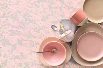 Set of stylish dinnerware on pink grunge background