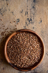 Raw organic buckwheat in a wooden bowl. Top view with copy space.