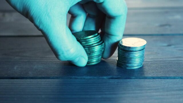 Selective focus - A woman puts columns of coins, a stack of cash collapsed. The concept of the growth and fall of the currency exchange rate. Appreciation and depreciation of money.