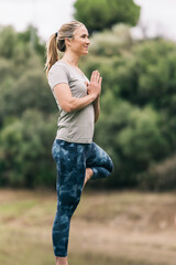 Woman standing doing yoga outside surrounded by nature