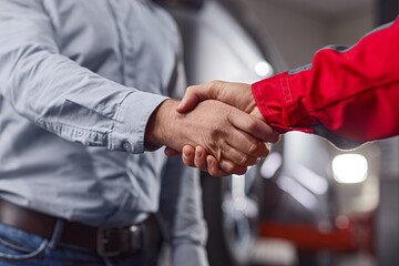 Car mechanic and customer shaking hands in workshop