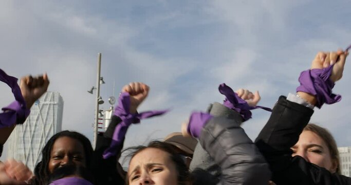 group of women with raised fists shouting slogans in feminist protest