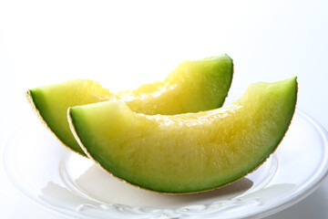 カットしてお皿に乗せたマスクメロン　白背景