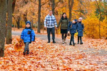 Portrait of a family with children in an autumn city park - happy people walking together, beautiful nature with yellow leaves as background.