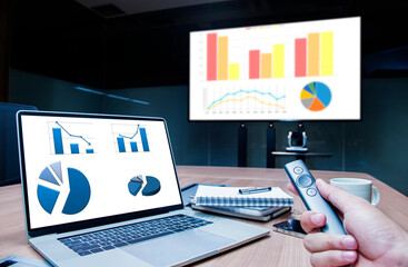 Businessman hand hold remote control slide with mock up chart slide show presentation on display...