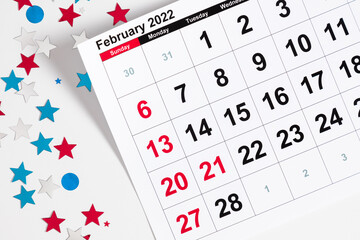 Presidents Day. Date on calendar February 21, 2022. Red, blue and white star confetti, decorations on white background. Flat lay, top view, copy space