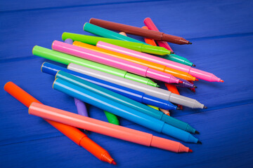 A set of different color markers on a blue background.