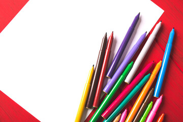Blank white paper and color markers on wooden table.