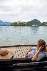 Fototapeta premium Young adult tourist woman sitting on a bench and enjoying on a lake.