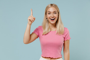 Young excited caucasian blonde woman 20s wear casual pink t-shirt holding index finger up with...