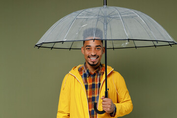 Vivid charming young black man 20s years old wears yellow raintcoat shirt hold umbrella look camera...