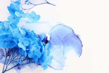 Creative image of blue Hydrangea flowers on artistic ink background. Top view with copy space