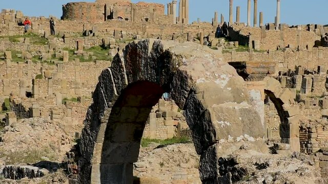 Group of people walking on Roman ruins in Djemila, in the front roman arches