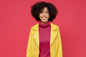 Charming bright happy swanky young curly black latin woman 20s years old wears yellow jacket looking camera smiling isolated on plain red background studio portrait. People emotions lifestyle concept.