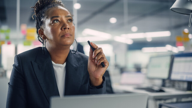 Busy African American Female Manager Using Computer In Modern Office. Overworked Tired Employee Dealing With Hard Work Tasks. Stressed Beautiful Woman Exhausted To Come Up With New Business Ideas.