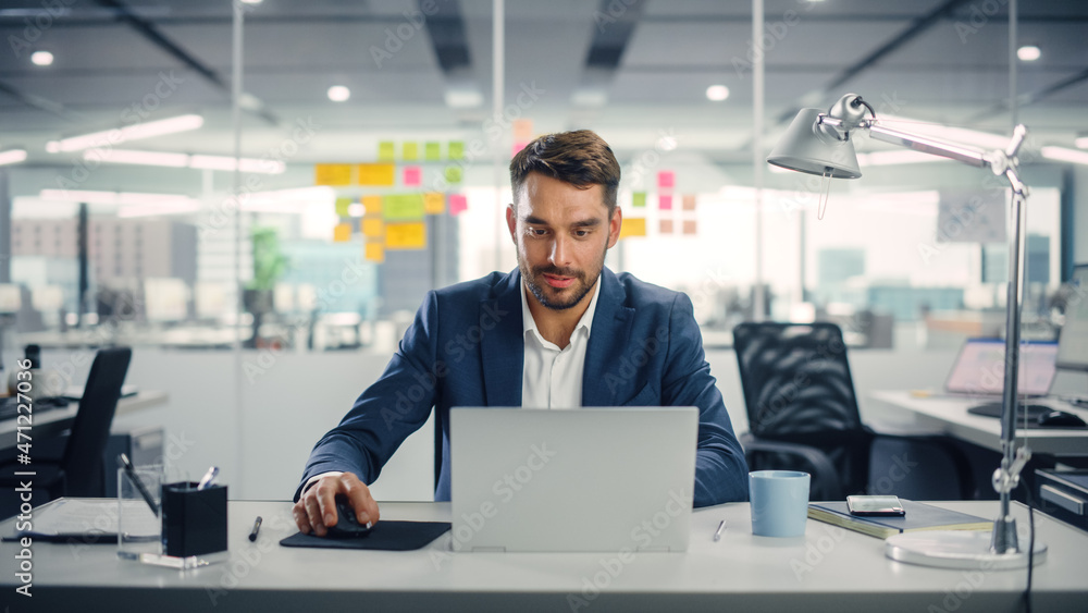 Poster young happy businessman using computer in modern office with colleagues. successful handsome manager