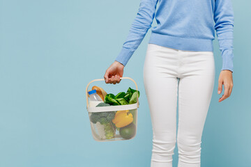 Cropped shot young woman 20s wearing casual sweater pants hold white busket with begetables ingredients isolated on plain pastel light blue background studio portrait. People lifestyle food concept.