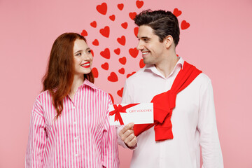 Young happy couple two friends woman man in casual shirt hold gift certificate coupon voucher card for store isolated on plain pastel pink background. Valentine's Day birthday holiday party concept