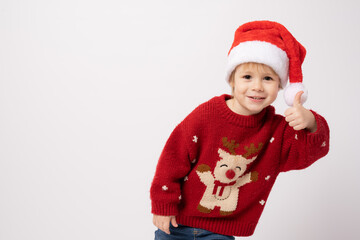 Cute little boy wearing santa hat with thumb up standing isolated over white background.