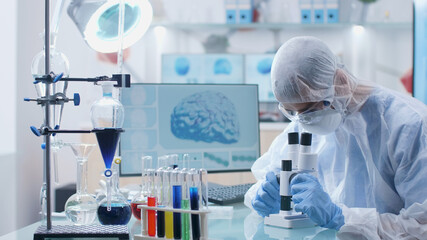 Scientist chemist analyzing blood sample using medical microscope during microbiology experiment in biochemistry hospital laboratory. Researcher doctor developing vaccine against covid19