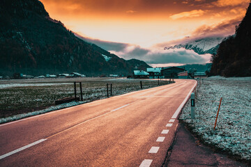 road at sunset leading to snow covered mountain peaks