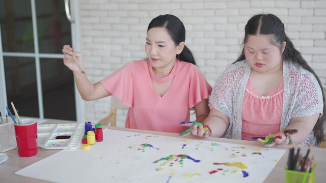 Asian girl with Down syndrome during art painting with mother at home
