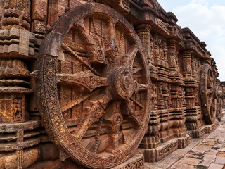 Fototapeta na wymiar Richly carved Chariot wheel with eight spokes with a central medallion. Deities and erotic and amorous figures shown. Konark Sun Temple, Orissa India