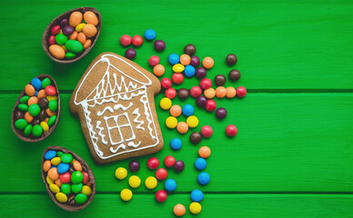 Gingerbread and colored sweets on a green  wooden background.  Place for text or logo.