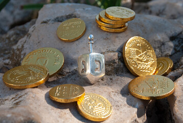 A small, silver Hanukkah dreidel showing the Hebrew letters 