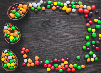 Chocolate easter eggs and colored sweets on a wooden background.