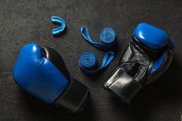 Boxing gloves with mouthguard and blue boxing bandages on a black background