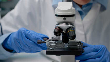 Close up of scientific microscope in laboratory and specialist hands using lens with magnifying...