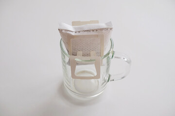 Unopened drip bag coffee on glass cup. Instant freshly brewing method