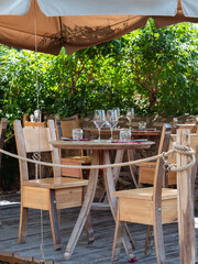 Empty Wooden Tables with Crystal Wine tasting Glasses Set for Outdoor Lunch in a Tuscan Village in Italy