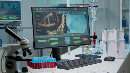 Close up of laboratory desk in hospital clinic with modern equipment and instruments for biochemistry research. Workplace with microscope, vacutainers, pipette and computer for innovation