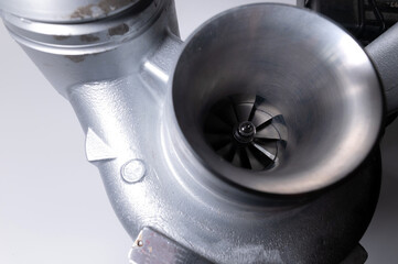 Close-up of an auto part for an internal combustion engine. Gas turbine. Turbo supercharger new on a gray background. Parts background