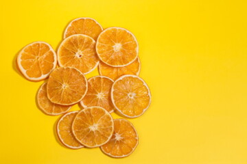 Dried slices of orange fruit on yellow paper background 