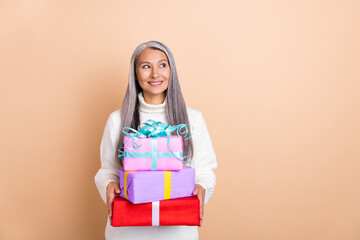 Photo of curious lady hold stack giftboxes look empty space wear white pullover isolated beige...