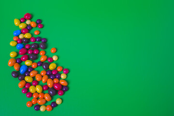 Colored candies on green background.