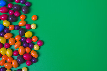 Colored candies on green background.
