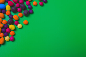 Colored candies on green background.