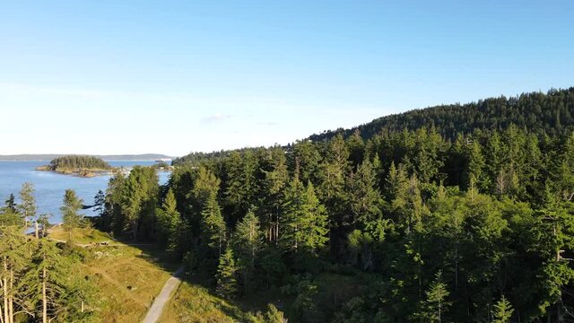 Ascending aerial footage of Neck point park in Nanaimo, British Columbia. Vancouver Islands east coast during sunset filmed from above in ultra HD. Coniferous forest on the shore of the Salish sea.
