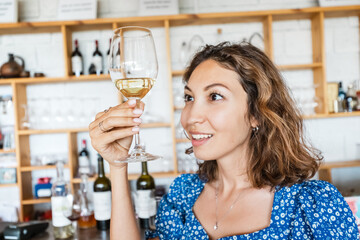 Smiling woman tastes young white wine at a winery during a special tour. The concept of bouquets and new flavors of the best grape and table varieties.