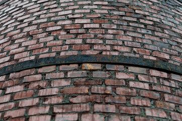 gray-red old brick slightly semicircular wall with a metal rusty strip