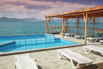 Sun loungers and sunbeds near the swimming pool with view on Lake Sevan in Armenia. Rest and vacation concept