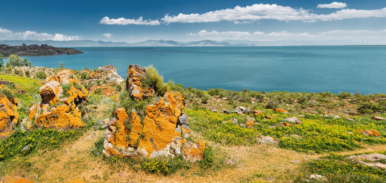 Idyllic landscape with scenic orange rocks and famous Lake Sevan - one of the largest sources of fresh water in Armenia and the whole Transcaucasia.