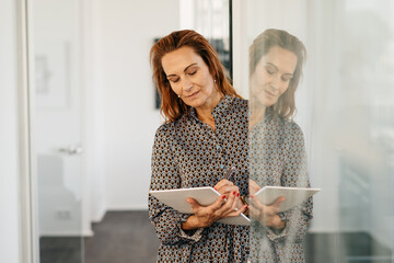 Dedicated businesswoman standing writing notes with reflection