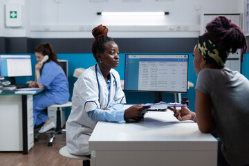 African american physician discussing disease symptoms questionnaire with sick woman patient during clinical appointment working in hospital office. Practitioner doctor explaining healthcare treatment