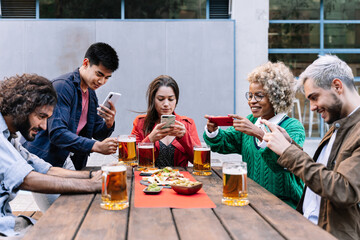 Group of happy multi ethnic friends with smartphones taking picture of food and drink at outdoors...
