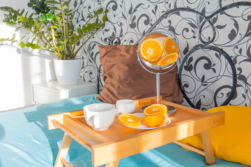 A man at home takes care of himself and does a manicure at home on a blue background and with oranges.
